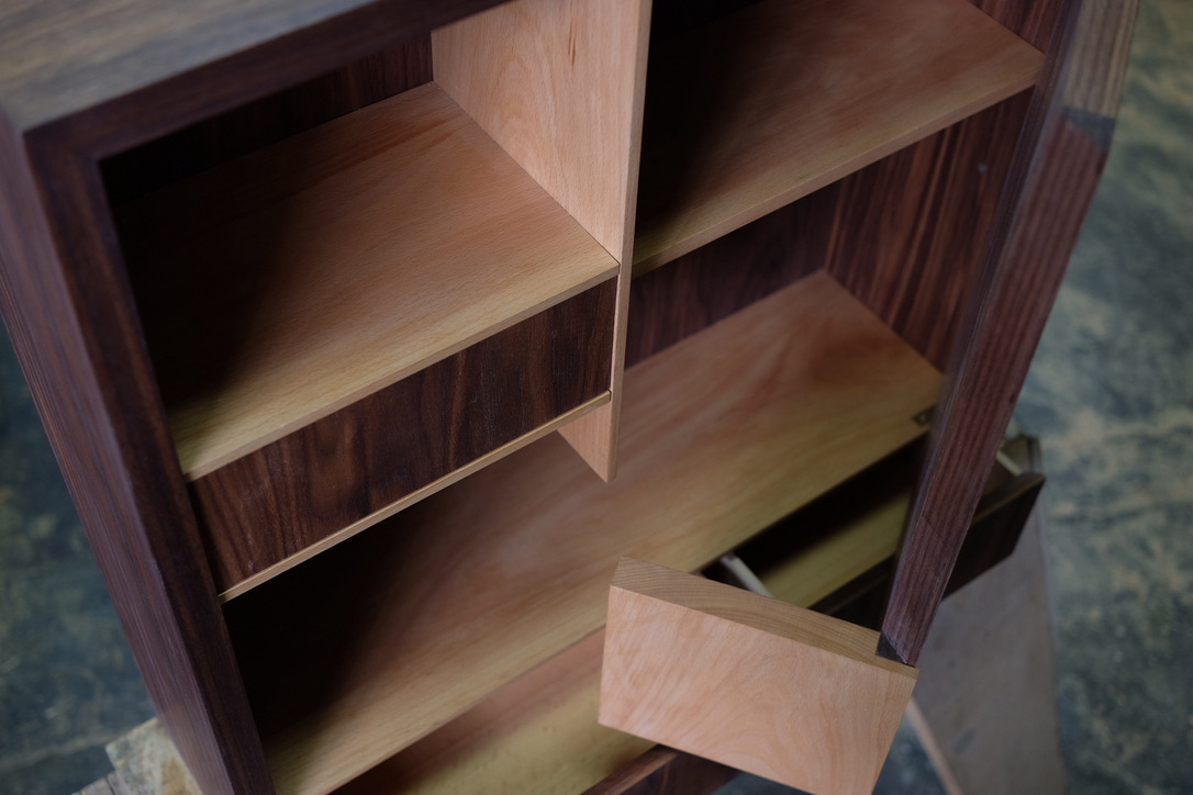 Walnut cabinet with open shelves and pull-out drawer showing interior joinery