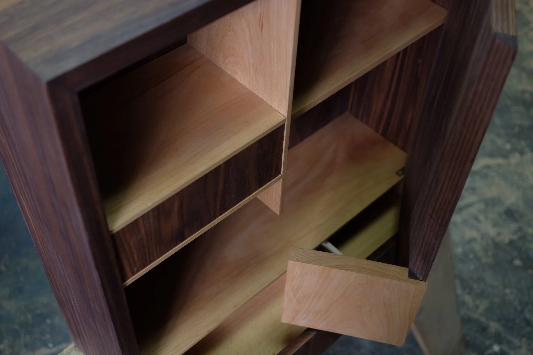 Interior of a custom walnut cabinet with beech shelves, dovetail drawers, and integrated compartments by Flatow Furniture