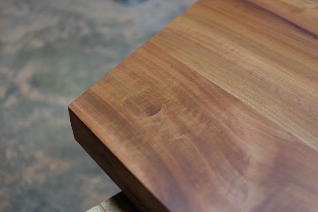 Close-up of a madrone desk with a circular replaceable wooden plug